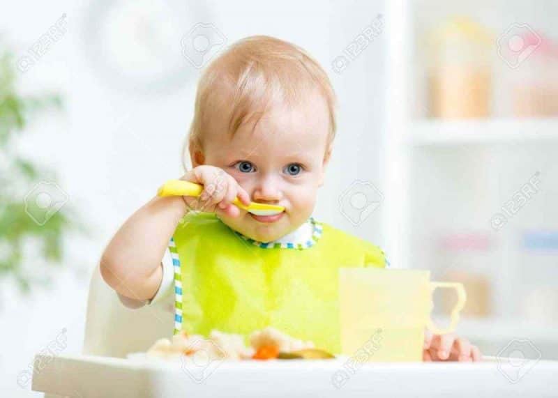 37330758-happy-baby-child-sitting-in-chair-with-a-spoon-stock-photo-baby-food-eating