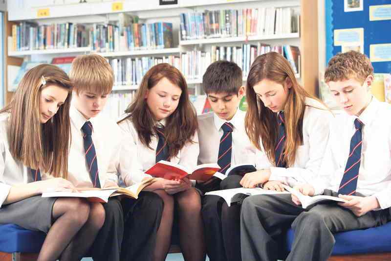 Teenage Students In Library Reading Books